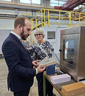 Dezernatsleiter Thomas Hahn erklärt Staatssekretärin Silke Krebs das Brandverhalten unterschiedlicher Baustoffe