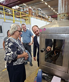 Dezernatsleiter Thomas Hahn erklärt Staatssekretärin Silke Krebs das Brandverhalten unterschiedlicher Baustoffe